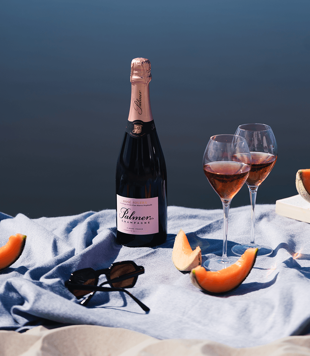 Champagne Palmer Rose Solera pictured on picnic blanket with sunglasses and melon slices
